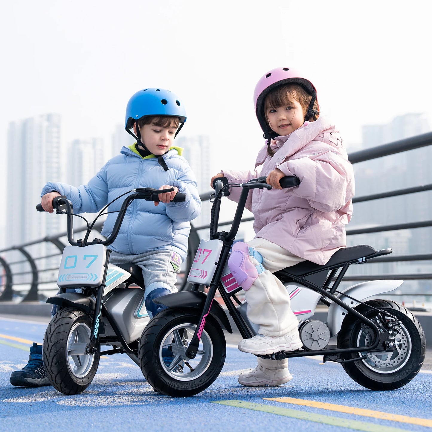 Deux enfants conduisant une moto électrique 250W chacun, version bleue et rose, port de casque.
